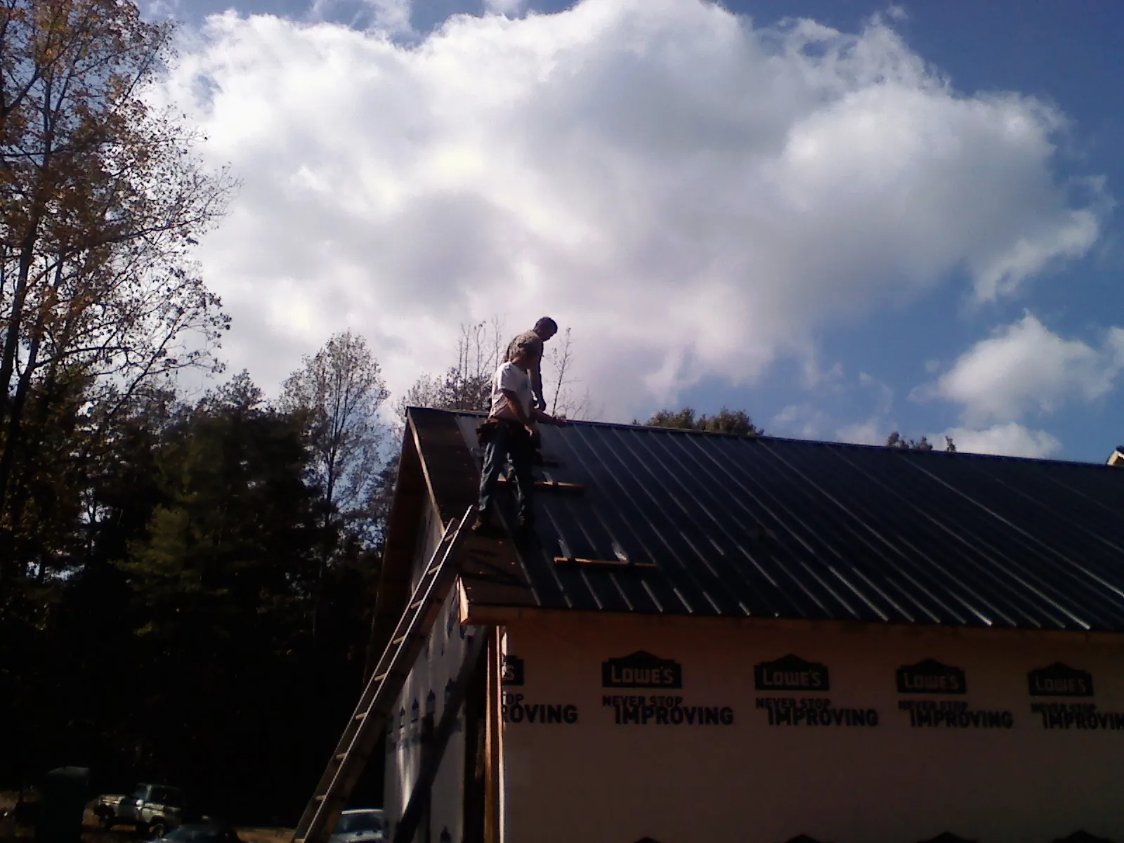 Roofer fastening dark metal panels high against a cloudy sky, from a Roof Inspection job in Stevenson