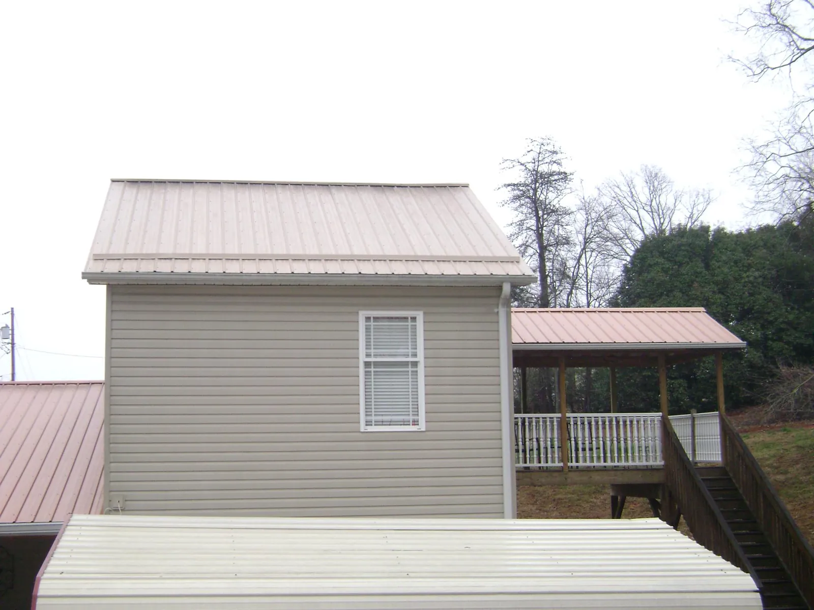 Tan metal roofs on a two story addition and attached porch, from a Roof Replacement job in Stevenson