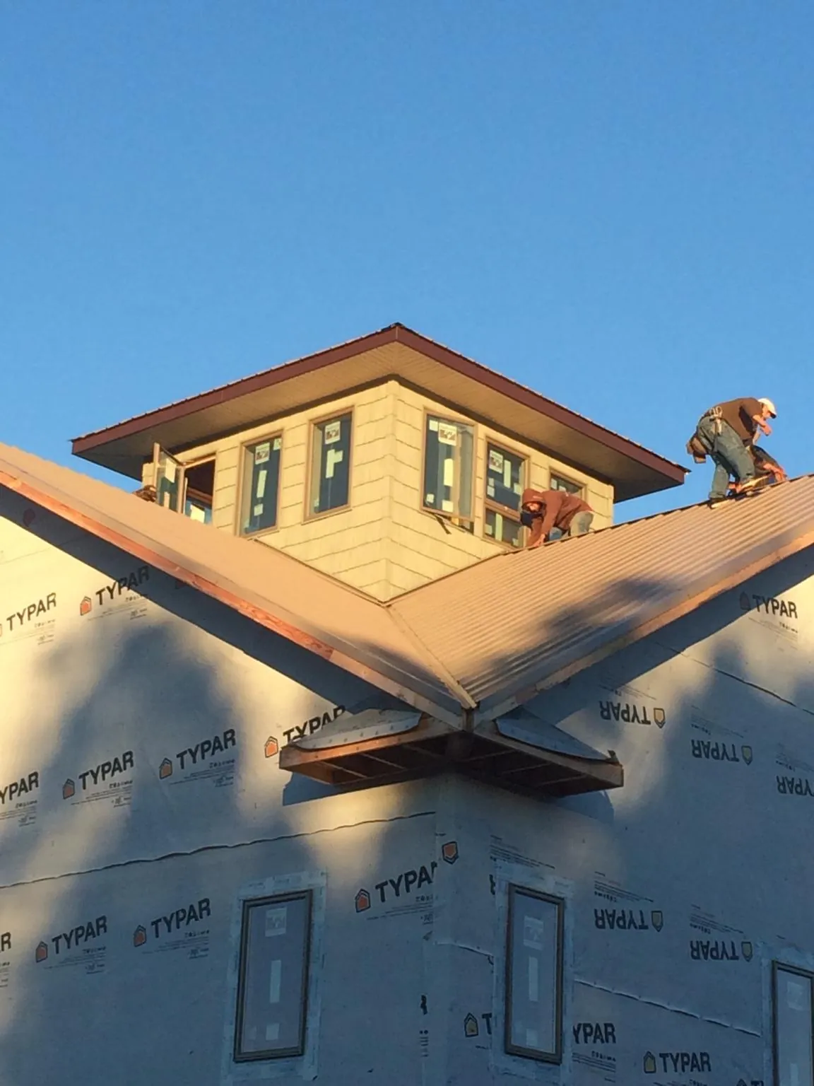 Roofers working around a rooftop cupola on a new metal roof at sunset — Roof Waterproofing in Stevenson by Roofing Brothers
